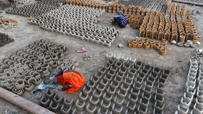 Women make clay stoves to be sold to the devotees who will be staying on the banks of the Ganges river. ( (AP Photo/Rajesh Kumar Singh))