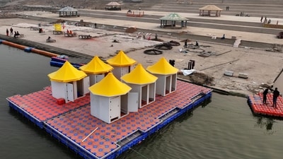 Workers make a floating platform on the Ganges river from interlocking plastic cubes, right, next to a finished one supporting changing rooms for the VIPs. ( (AP Photo/Rajesh Kumar Singh))