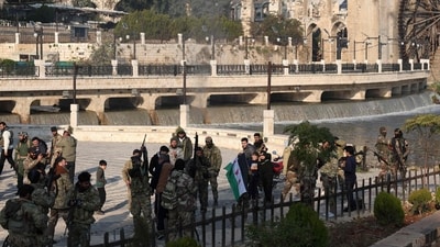 Syrian anti government fighters gather among civilians near of one of Hama's water wheels, or norias, after forces captured of the city of Hama on December 6, 2024.&nbsp; (AFP)