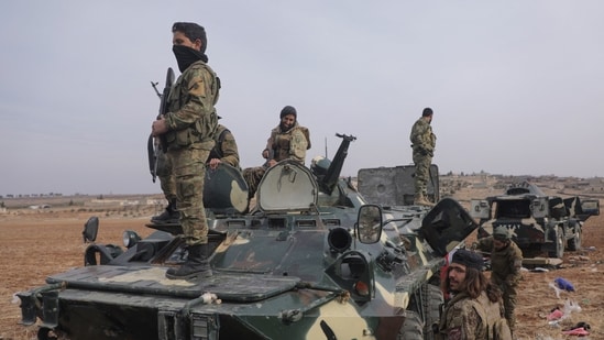 Syria Crisis Live: Rebel fighters stand on a military vehicle in Homs countryside