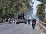 People ride a tank in the Syrian southern city of Daraa after the collapse of government forces.