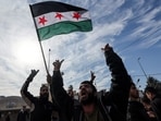 A man waves a Syrian opposition flag as people people celebrate at Masnaa Border Crossing, after Syrian rebels announced that they have ousted President Bashar al-Assad, Lebanon,