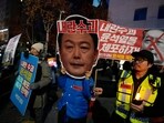 A participant wearing a mask of South Korean President Yoon Suk Yeol attends a rally demanding his impeachment outside the National Assembly in Seoul, South Korea,.The signs read "Arrest Yoon Suk Yeol."