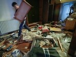 A man walks by a broken portrait of the late Syrian President Hafez Assad as people search for belongings in the ransacked private residence of Syrian President Bashar Assad in the Malkeh district of Damascus