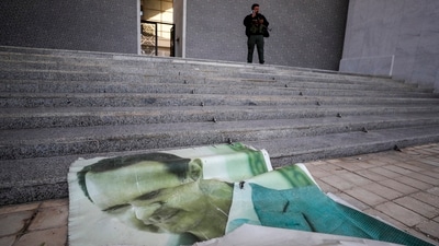 A giant picture of Syrian President Bashar Assad lies on the ground as a Syrian opposition fighter stands nearby, inside the Presidential Palace in Damascus, Syria, Sunday, Dec. 8, 2024. AP/PTI(AP12_08_2024_000124B) (AP)