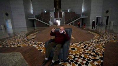 An old Syrian man posed for a picture on a chair flashing a victory sign inside the Syrian presidential palace. Storerooms and cupboards in the palace were also emptied out as citizens explored the palace under minimal armed presence (AP)