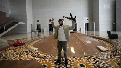 A man held an AK-47 and flashed the victory sign as he posed for a photo in a hall of president Bashar al-Assad's presidential palace. (AP)