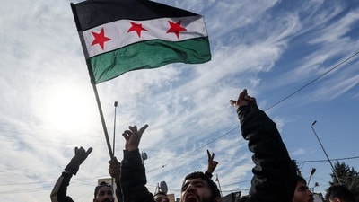A man waves a Syrian opposition flag as people people celebrate at Masnaa Border Crossing, after Syrian rebels announced that they have ousted President Bashar al-Assad, Lebanon, (REUTERS)