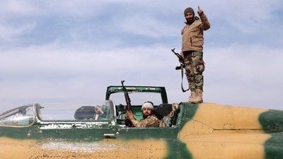Rebel fighters gesture as they check a Syrian army jet after they took over a military airbase near the central city of Hama. (AFP) Rebel fighters gesture as they check a Syrian army jet after they took over a military airbase near the central city of Hama. (AFP)