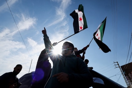 A person waves a Syrian opposition flag as people celebrate at Masnaa Border Crossing, after Syrian rebels announced that they have ousted President Bashar al-Assad, (REUTERS)