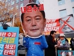 A protestor wears a cut-out of South Korean President Yoon Suk Yeol in a rally calling for his impeachment, who declared martial law, which was reversed hours later, near the National Assembly in Seoul, South Korea.