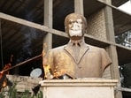 Flames rise near a damaged statue of former Syrian president Hafez al-Assad, after rebels seized the capital and ousted President Bashar al-Assad, in Qamishli.