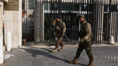 Rebel fighters walk in front of Syrian Central Bank, after rebels seized the capital and ousted President Bashar al-Assad, in Damascus, Syria, December 9, 2024. (REUTERS)