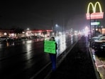 A person holds a sign while standing on the roadside near the McDonald's restaurant where Luigi Mangione was arrested.