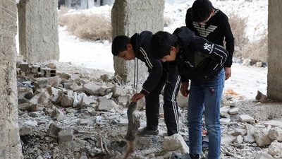 Kids search and inspect bones amidst rubbles after what residents and rights groups described as years of killings there under the rule of Syria's Bashar al-Assad. (REUTERS)