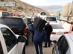 A man carries a suitcase on his shoulders while walking towards the Lebanese border, at the Masnaa Border Crossing, Syria, December 12, 2024. 