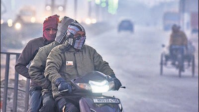 People braving the cold on their way to work on the Sector-37C road in Gurugram on Friday. (Parveen Kumar/Hindustan Times)