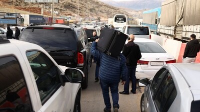 A man carries a suitcase on his shoulders while walking towards the Lebanese border, at the Masnaa Border Crossing, Syria, December 12, 2024. (REUTERS)