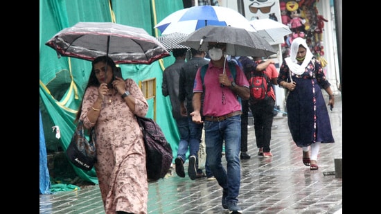 People holding umbrellas at Brigade Road, following heavy rain in Bengaluru (HT PHOTO)