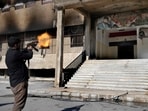 A Syrian fighter from rebel group, fires towards a poster at the entrance of the notorious security detention centre called Palestine Branch, which pictures the late Syrian President Hafez Assad and his son the ouster Syrian president Bashar Assad, in Damascus, Syria, Saturday, Dec. 14, 2024. A Syrian fighter from rebel group, fires towards a poster at the entrance of the notorious security detention centre called Palestine Branch, which pictures the late Syrian President Hafez Assad and his son the ouster Syrian president Bashar Assad, in Damascus, Syria, Saturday, Dec. 14, 2024.