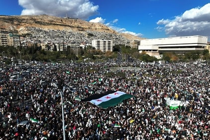 An aerial photo shows crowds of Syrians raising a giant independence-era flag, used by the opposition since the uprising began in 2011, as they celebrate the fall of Bashar al-Assad's iron-fisted rule earlier this week at the central Umayyad Square in Damascus on December 13, 2024. (AFP) An aerial photo shows crowds of Syrians raising a giant independence-era flag, used by the opposition since the uprising began in 2011, as they celebrate the fall of Bashar al-Assad's iron-fisted rule earlier this week at the central Umayyad Square in Damascus on December 13, 2024. (AFP)