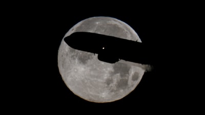 A passenger plane passes in front of the moon near the Fiumicino airport, in Rome, Italy, on December 15. (REUTERS)