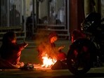 People sit around a bonfire to beat the cold in Noida on December 15, 2024. (Sunil Ghosh/ HT Photo) 