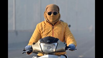 A commuter with her face covered in cloth, rides along a street amid smog in Amritsar on December 16, 2024. (AFP)