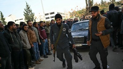 Members of Syria's new authorities walk followed by a car as Syrian soldiers, (AFP) Members of Syria's new authorities walk followed by a car as Syrian soldiers, (AFP)