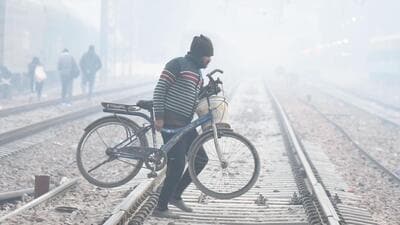 A man carrying his bicycle across railway tracks in the smog on a cold winter morning at Daultabad near Railway Station, in Gurugram on Tuesday. (Parveen Kumar/Hindustan Times) A man carrying his bicycle across railway tracks in the smog on a cold winter morning at Daultabad near Railway Station, in Gurugram on Tuesday. (Parveen Kumar/Hindustan Times)