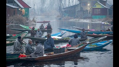 Vegetable sellers row their boats at a floating wholesale market on Dal Lake during a cold day as Srinagar on Wednesday. (PTI) Vegetable sellers row their boats at a floating wholesale market on Dal Lake during a cold day as Srinagar on Wednesday. (PTI)