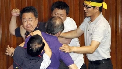 Ruling and opposition lawmakers fought on the legislature floor in Taiwan. They exchanged punches and threw water at each other ahead of an expected vote. (AP Photo) 