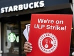 Former employees and supporters join unionized Starbucks employees as they carry signs in support of a strike, outside of a Starbucks store in Arlington, Virginia, on November 16, 2023
