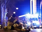 Germany car attack: Two rescuers sit on the ground to rest after a car crashed into a crowd at a Christmas market, injuring more than 60 people on December 20, 2024, in Magdeburg, eastern Germany.&nbsp;
