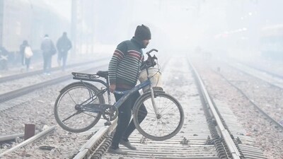 A man carrying his bicycle across railway tracks on a cold winter morning at Daultabad near Railway Station, in Gurugram on December 17. (Parveen Kumar/Hindustan Times) A man carrying his bicycle across railway tracks on a cold winter morning at Daultabad near Railway Station, in Gurugram on December 17. (Parveen Kumar/Hindustan Times)