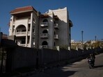 Men ride a motorcycle past a property owned by ousted Syrian President Bashar Assad's family in Qardaha, Syria, on Tuesday,