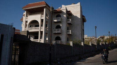 Men ride a motorcycle past a property owned by ousted Syrian President Bashar Assad's family in Qardaha, Syria, on Tuesday, (AP) Men ride a motorcycle past a property owned by ousted Syrian President Bashar Assad's family in Qardaha, Syria, on Tuesday, (AP)