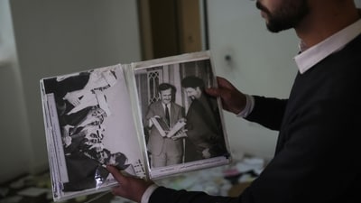 A man shows old pictures of the late Syrian President Hafez Assad as people search for belongings in the ransacked private residence of Syrian President Bashar Assad in the Malkeh district of Damascus, Syria, on Sunday, Dec. 8, 2024. (AP) A man shows old pictures of the late Syrian President Hafez Assad as people search for belongings in the ransacked private residence of Syrian President Bashar Assad in the Malkeh district of Damascus, Syria, on Sunday, Dec. 8, 2024. (AP)