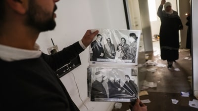 A man shows old pictures of the late Syrian President Hafez Assad as civilians ransack the private residence of overthrown President Bashar Assad in the Malkeh district of Damascus, Syria, on Sunday, Dec. 8, 2024. (AP) A man shows old pictures of the late Syrian President Hafez Assad as civilians ransack the private residence of overthrown President Bashar Assad in the Malkeh district of Damascus, Syria, on Sunday, Dec. 8, 2024. (AP)
