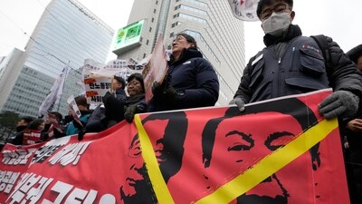 Protesters hold a banner showing images of impeached president Yoon Suk Yeol and acting President Han Duck-soo (AP)