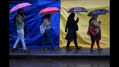TOPSHOT - People holding umbrellas walk along a street as it rains due to the influence of Cyclone Fengal, in Bengaluru on December 1, 2024. (Photo by IDREES MOHAMMED / AFP) (AFP)