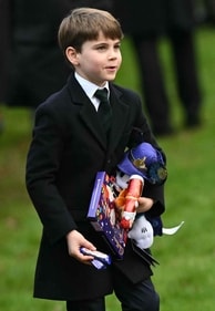 Britain's Prince Louis of Wales reacts as he carries gifts from wellwishers (AFP)