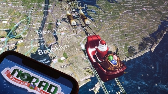 (FILES) This illustration photo shows the NORAD logo on a cell phone screen while the tracker follows Santa flying over New York City on a computer monitor in Los Angeles on December 24, 2023. (AFP)