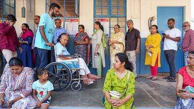 A volunteer assists an elderly voter in wheelchair at a polling station in Bengaluru during the Lok Sabha elections in April 2024. (PTI Photo)