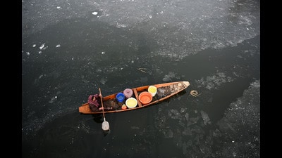 A woman rowing her boat through a frozen Dal Lake in Srinagar on Thursday. (Waseem Andrabi /HT)