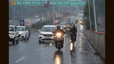 Commuters brave the chill and rain in Chandigarh on Friday. (Keshav Singh/HT)
