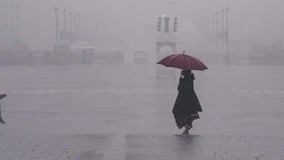 People move amid rain at Vijay Chowk, in New Delhi on Friday, (PTI) People move amid rain at Vijay Chowk, in New Delhi on Friday, (PTI)