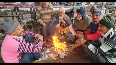 People sit around a bonfire in Bathinda on Saturday. Rain lashed parts of Punjab and Haryana for a second consecutive day on Saturday, causing day-temperatures to dip in both states. (Sanjeev Kumar/HT)