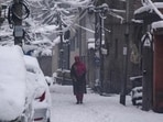 A woman walking on a snow-covered street in Srinagar on Saturday. Heavy snowfall blocked the Srinagar-Jammu national highway and roads in several districts. (PTI Photo)