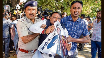 Police detain a BJP worker at a protest against minister Priyank Kharge in Bengaluru on Tuesday. (PTI) Police detain a BJP worker at a protest against minister Priyank Kharge in Bengaluru on Tuesday. (PTI)
